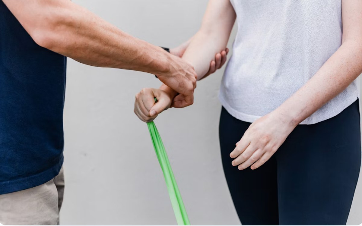 A therapist guiding a patient through a resistance band exercise.